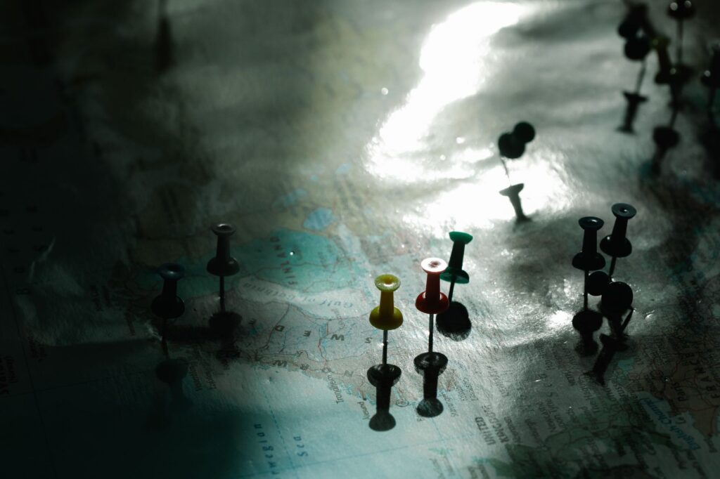 Close-up of colorful pushpins on a map, highlighting specific locations, with soft lighting and shadows.