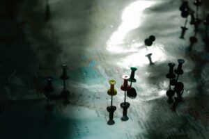 Close-up of colorful pushpins on a map, highlighting specific locations, with soft lighting and shadows.